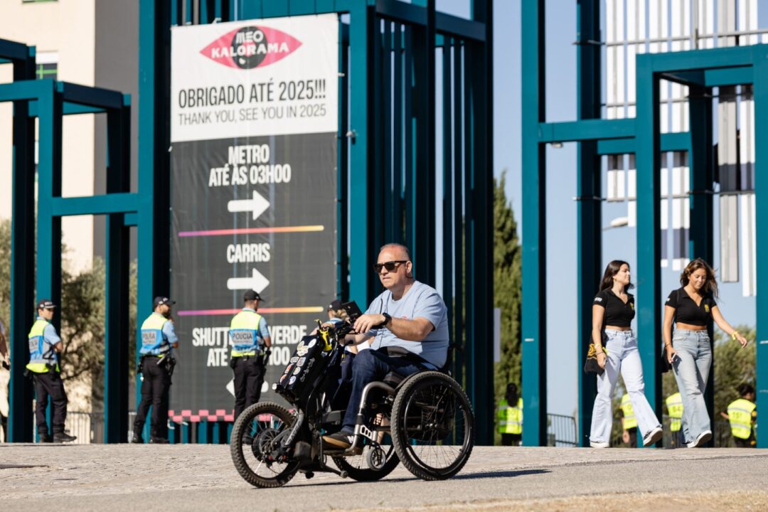 Homem em cadeira de rodas motorizada a sair do MEO Kalorama com sinal de agradecimento até 2025.