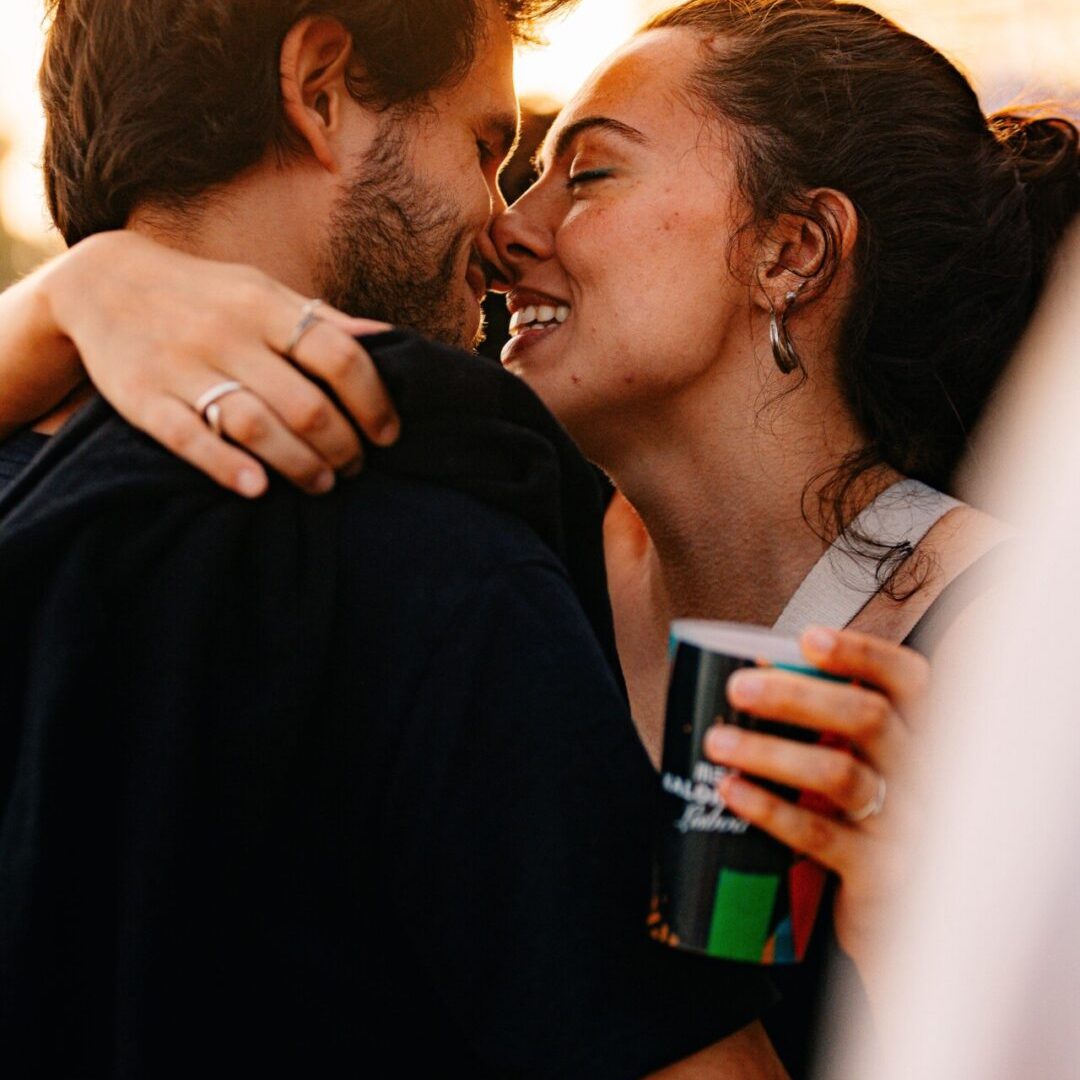 Casal a abraçar-se e a trocar um beijo durante o pôr do sol no festival.