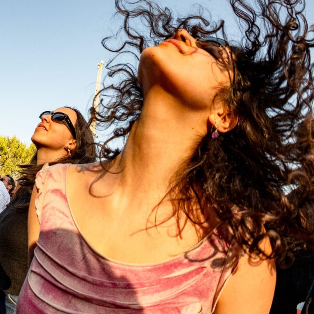 Mulher a dançar com o cabelo solto ao vento durante concerto do festival MEO Kalorama.